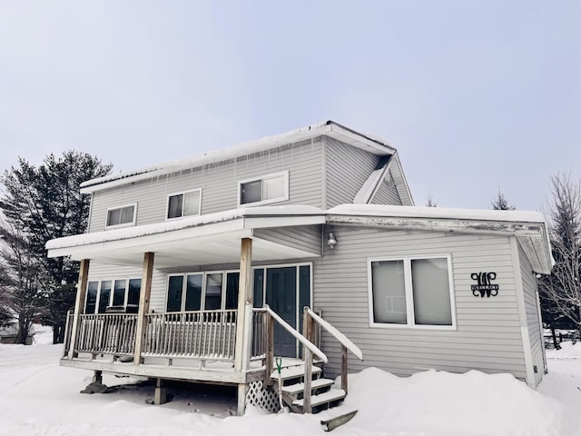 snow covered house featuring covered porch