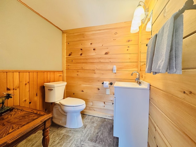 bathroom with toilet, vanity, and wooden walls