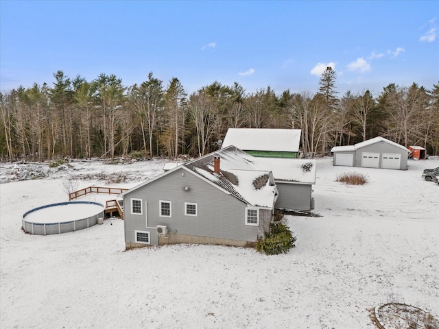 snow covered property featuring an outdoor structure and a garage