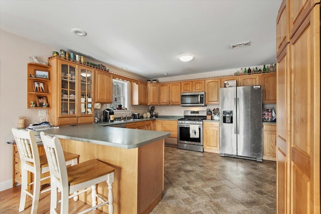 kitchen featuring kitchen peninsula, appliances with stainless steel finishes, a breakfast bar, and sink