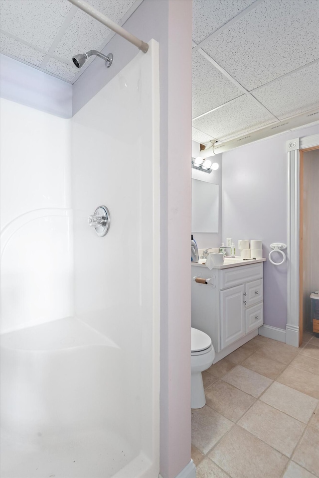 bathroom featuring a paneled ceiling, vanity, a shower, tile patterned flooring, and toilet