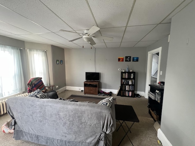 living room featuring ceiling fan, carpet, and a drop ceiling