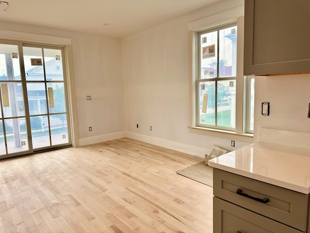 interior space featuring light stone countertops, light hardwood / wood-style floors, and gray cabinetry