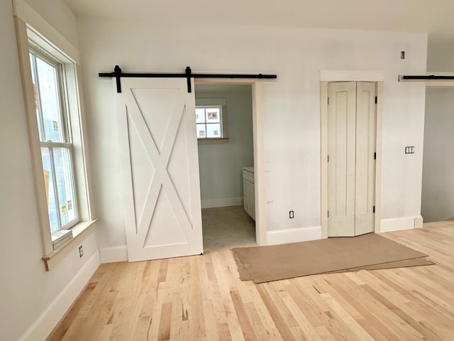 interior space with a barn door, a wealth of natural light, and light hardwood / wood-style floors