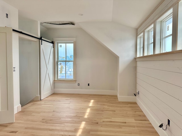 bonus room featuring a barn door, vaulted ceiling, and light wood-type flooring