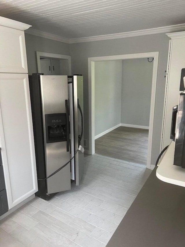 kitchen with white cabinets, stainless steel fridge, and crown molding