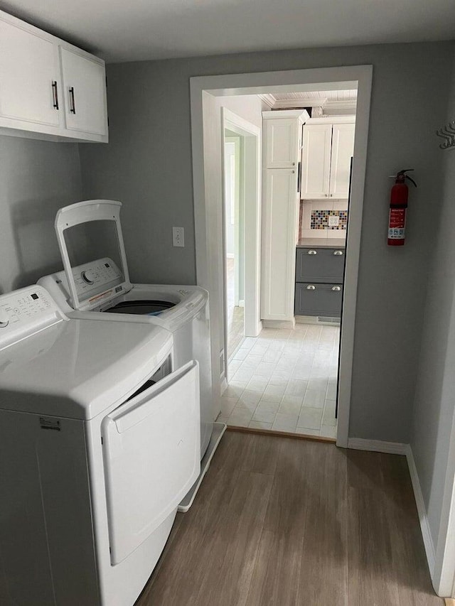 washroom featuring dark wood-type flooring, cabinets, and washing machine and clothes dryer