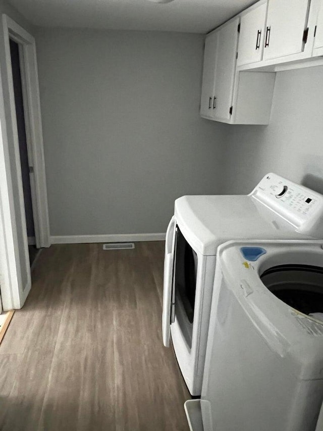 laundry room featuring cabinets, washer and dryer, and hardwood / wood-style flooring