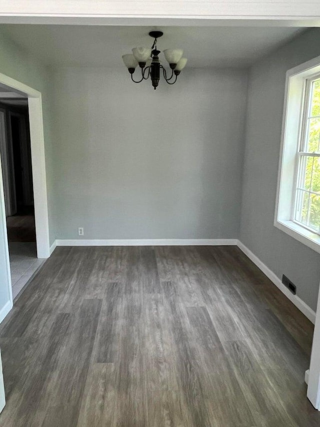 unfurnished dining area with a notable chandelier and dark hardwood / wood-style flooring