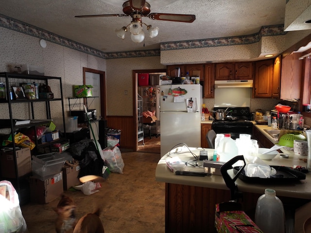 kitchen with black range with electric stovetop, wooden walls, ceiling fan, a textured ceiling, and white fridge