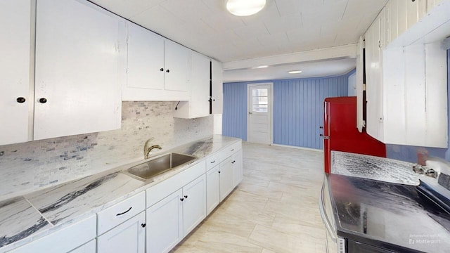 kitchen featuring stove, tasteful backsplash, white cabinetry, and sink