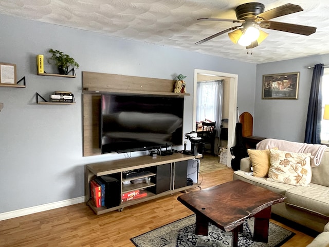 living room with hardwood / wood-style flooring, ceiling fan, and a textured ceiling