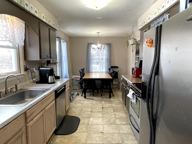 kitchen with sink, hanging light fixtures, stainless steel appliances, a notable chandelier, and a textured ceiling