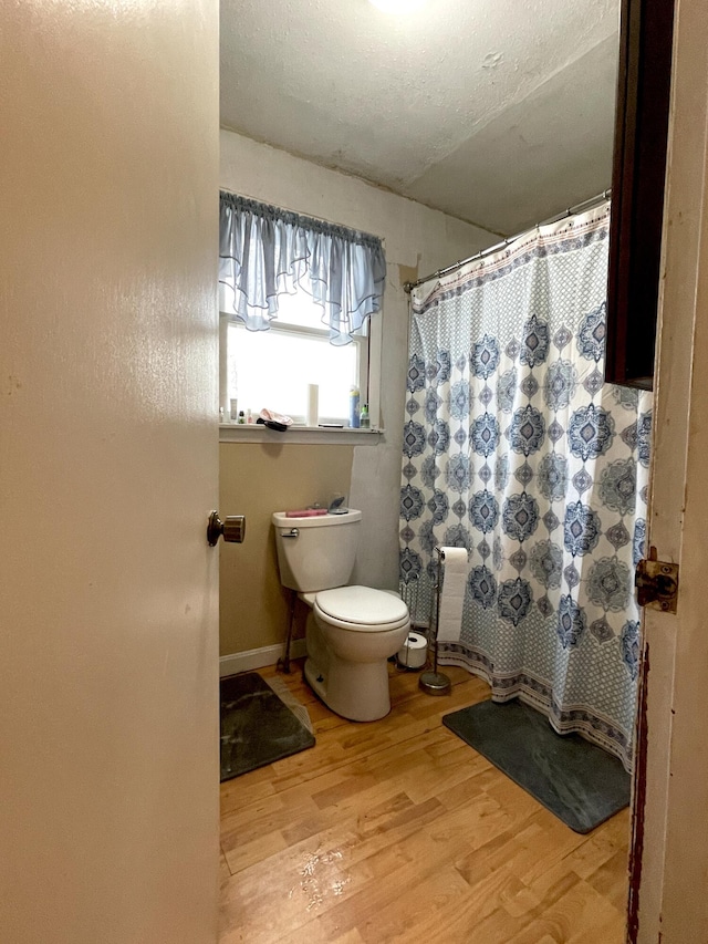 bathroom featuring wood-type flooring, a textured ceiling, and toilet