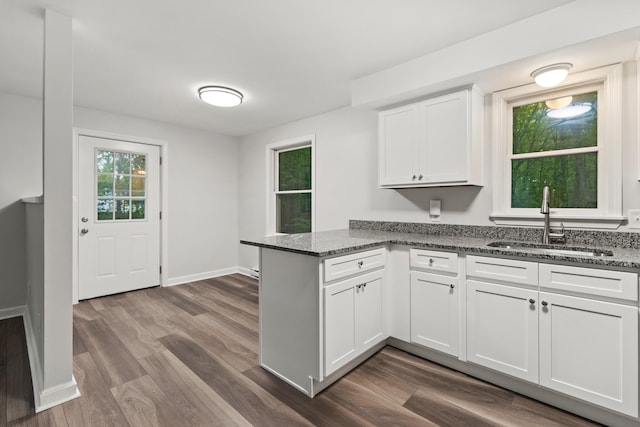 kitchen featuring white cabinetry, sink, dark wood-type flooring, kitchen peninsula, and dark stone countertops