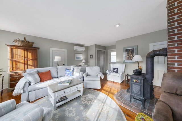 living room with a wall mounted air conditioner, hardwood / wood-style floors, and a wood stove