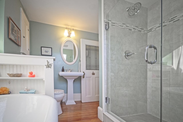 bathroom featuring hardwood / wood-style flooring, toilet, and a shower with shower door