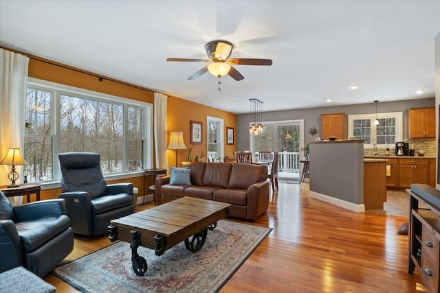 living room with sink, ceiling fan, a healthy amount of sunlight, and light wood-type flooring