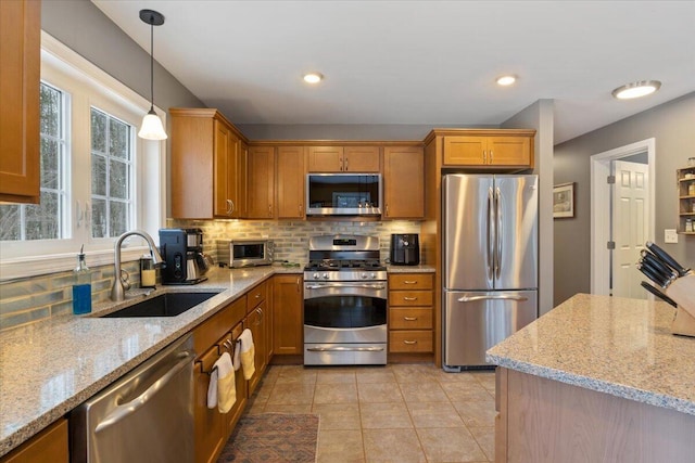 kitchen featuring sink, tasteful backsplash, light stone counters, and appliances with stainless steel finishes