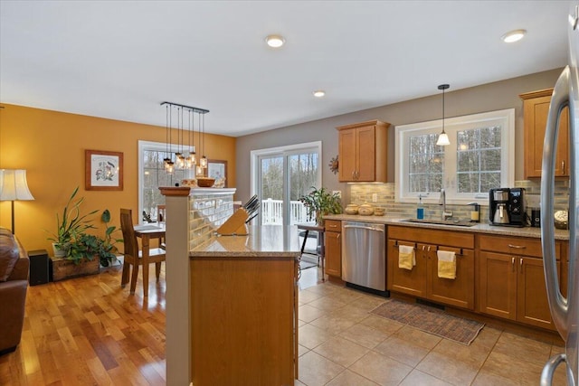 kitchen featuring sink, decorative light fixtures, light stone countertops, and appliances with stainless steel finishes