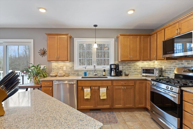 kitchen with appliances with stainless steel finishes, decorative backsplash, light stone countertops, and sink