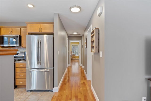 kitchen featuring light hardwood / wood-style floors, stainless steel appliances, light brown cabinetry, and tasteful backsplash