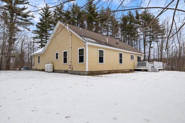 snow covered property with central air condition unit and a deck