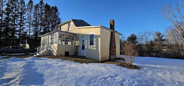 snow covered property featuring a sunroom