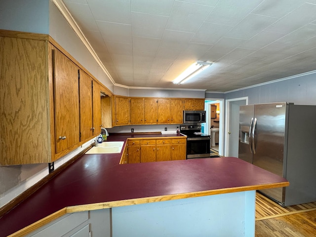 kitchen with sink, light wood-type flooring, kitchen peninsula, crown molding, and appliances with stainless steel finishes