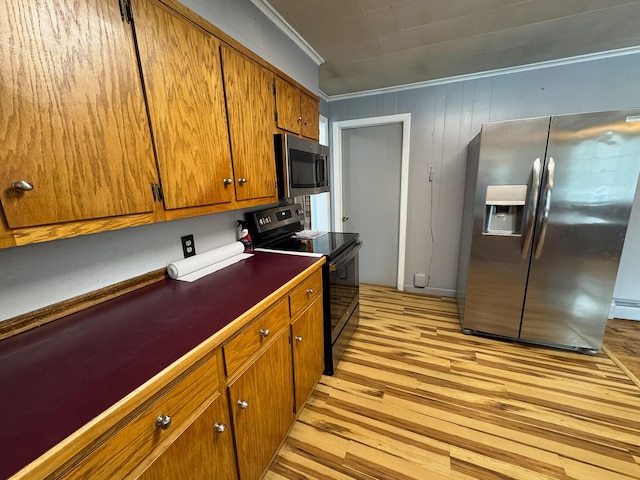 kitchen featuring stainless steel appliances, ornamental molding, and light hardwood / wood-style flooring