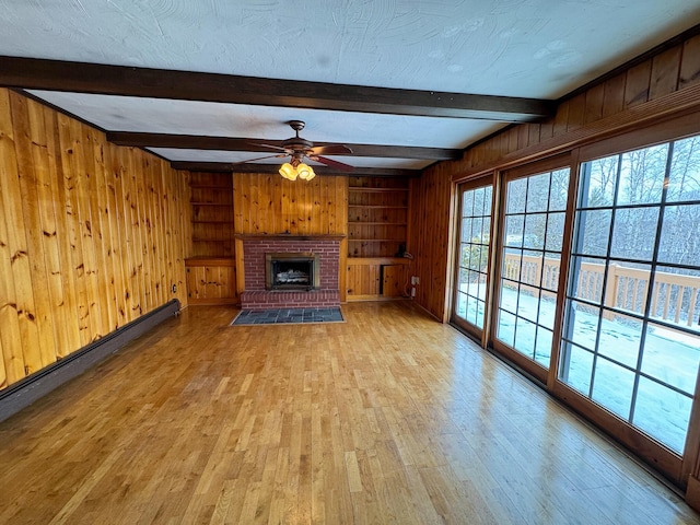 unfurnished living room with a fireplace, a textured ceiling, ceiling fan, built in features, and beam ceiling