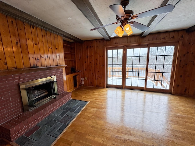 unfurnished living room with beam ceiling, a brick fireplace, and plenty of natural light