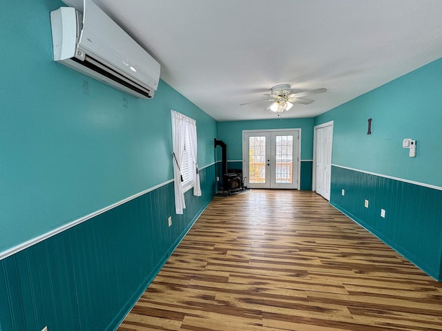 unfurnished room featuring ceiling fan, french doors, an AC wall unit, and wood-type flooring