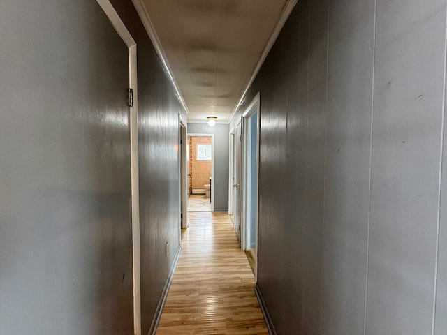 hall with light wood-type flooring and ornamental molding