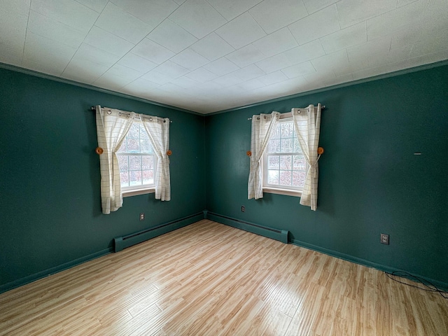 empty room featuring ornamental molding, plenty of natural light, and light hardwood / wood-style flooring