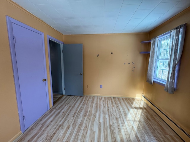 empty room featuring light wood-type flooring and a baseboard radiator