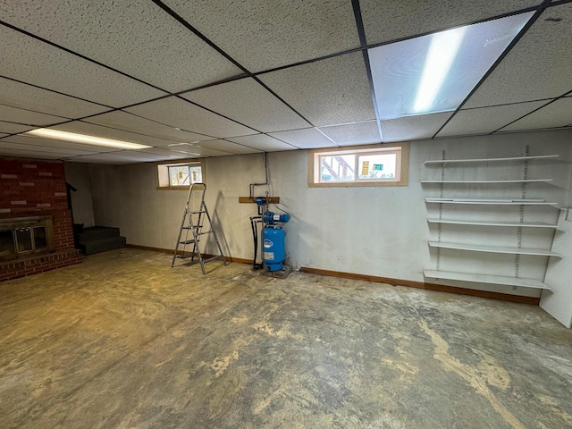 basement featuring a fireplace, a drop ceiling, and carpet