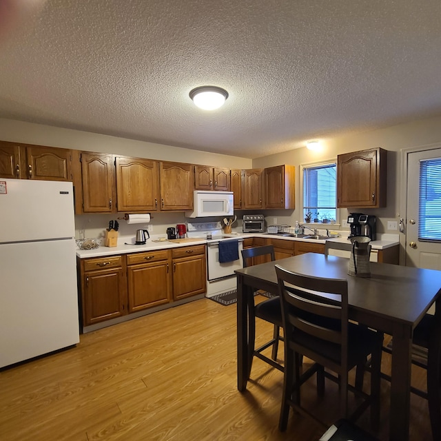 kitchen featuring a textured ceiling, white appliances, and light wood-type flooring