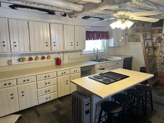 kitchen with sink, white cabinetry, radiator heating unit, and a breakfast bar area