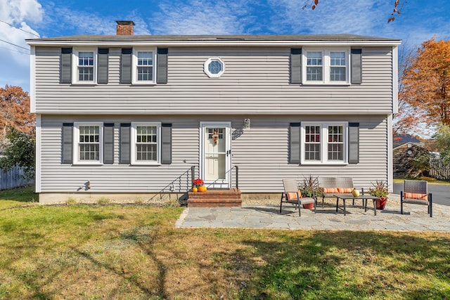 colonial home with a patio area and a front lawn