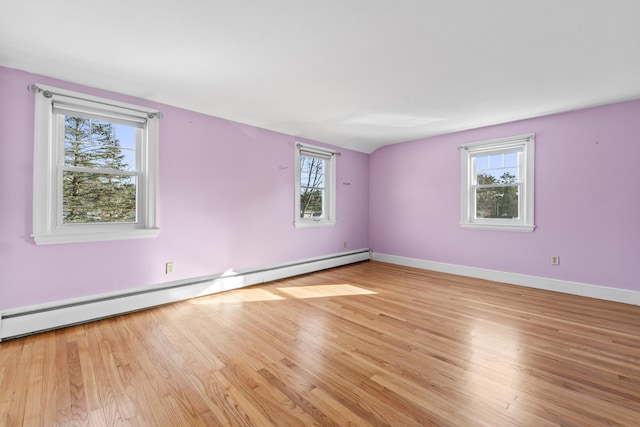 unfurnished room with baseboard heating, light hardwood / wood-style flooring, and vaulted ceiling