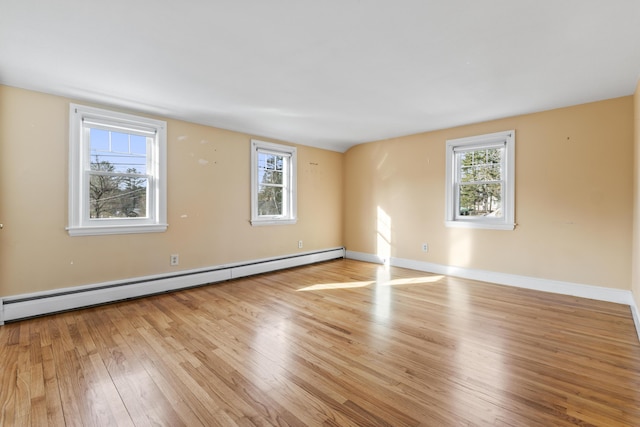 empty room featuring light hardwood / wood-style flooring, a baseboard radiator, and plenty of natural light