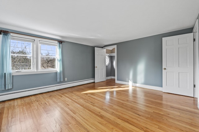 unfurnished bedroom with light hardwood / wood-style flooring and a baseboard heating unit