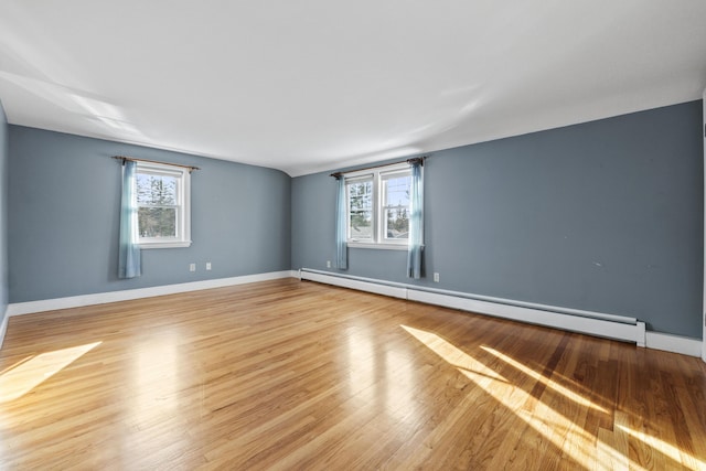 spare room with a healthy amount of sunlight, light hardwood / wood-style flooring, and a baseboard heating unit