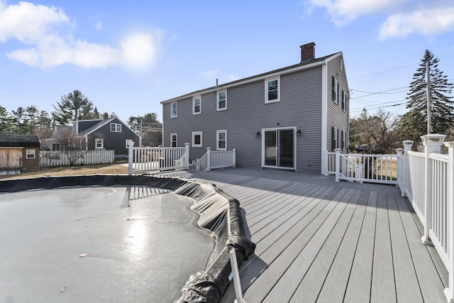 back of house featuring a wooden deck and a storage shed