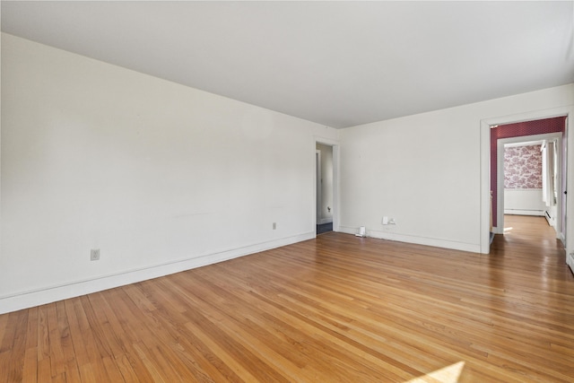 empty room featuring hardwood / wood-style flooring and a baseboard heating unit