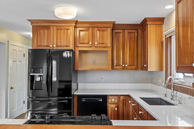 kitchen featuring light stone counters, sink, and black appliances