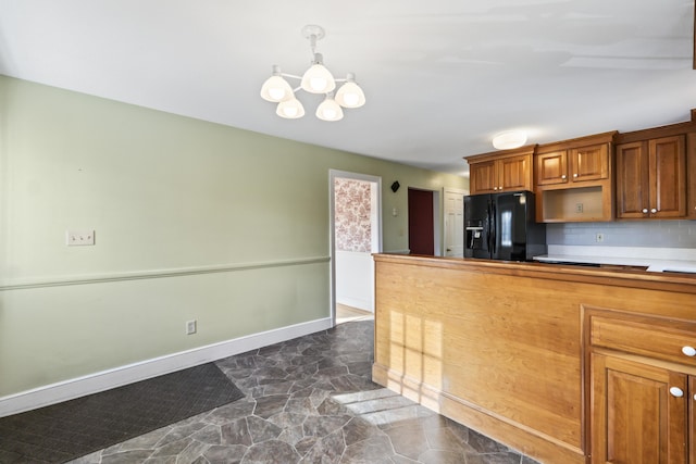 kitchen featuring a notable chandelier, black fridge, hanging light fixtures, and tasteful backsplash