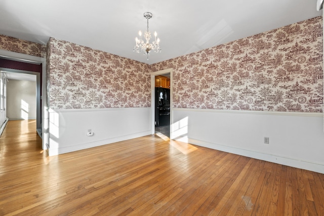 unfurnished room featuring hardwood / wood-style floors and an inviting chandelier