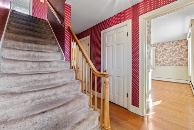 stairs featuring hardwood / wood-style floors and a baseboard radiator